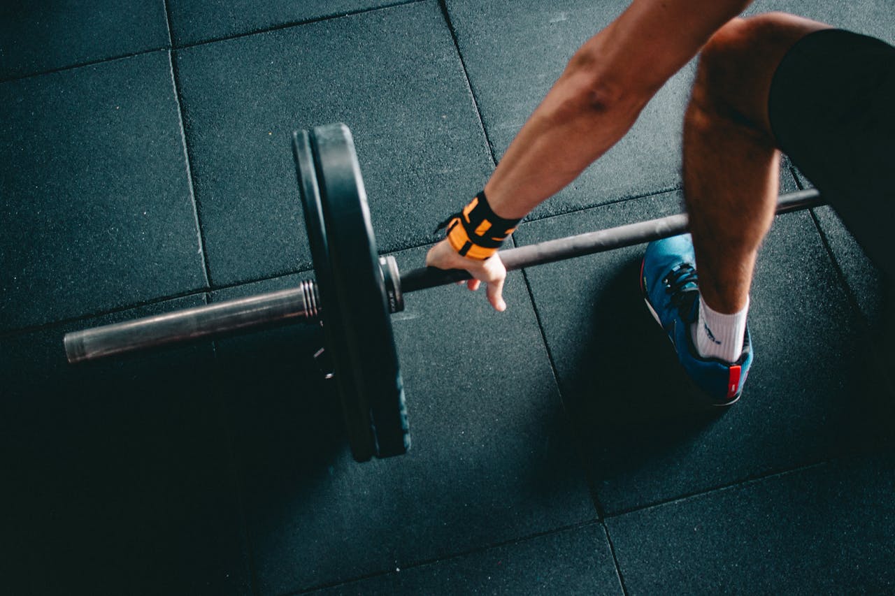 A modern gym interior with exercise equipment, weights, and a person lifting dumbbells