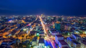 Overhead night Phnom Penh, Cambodia view of a sprawling cityscape with bright lights and a long road, symbolizing business growth.